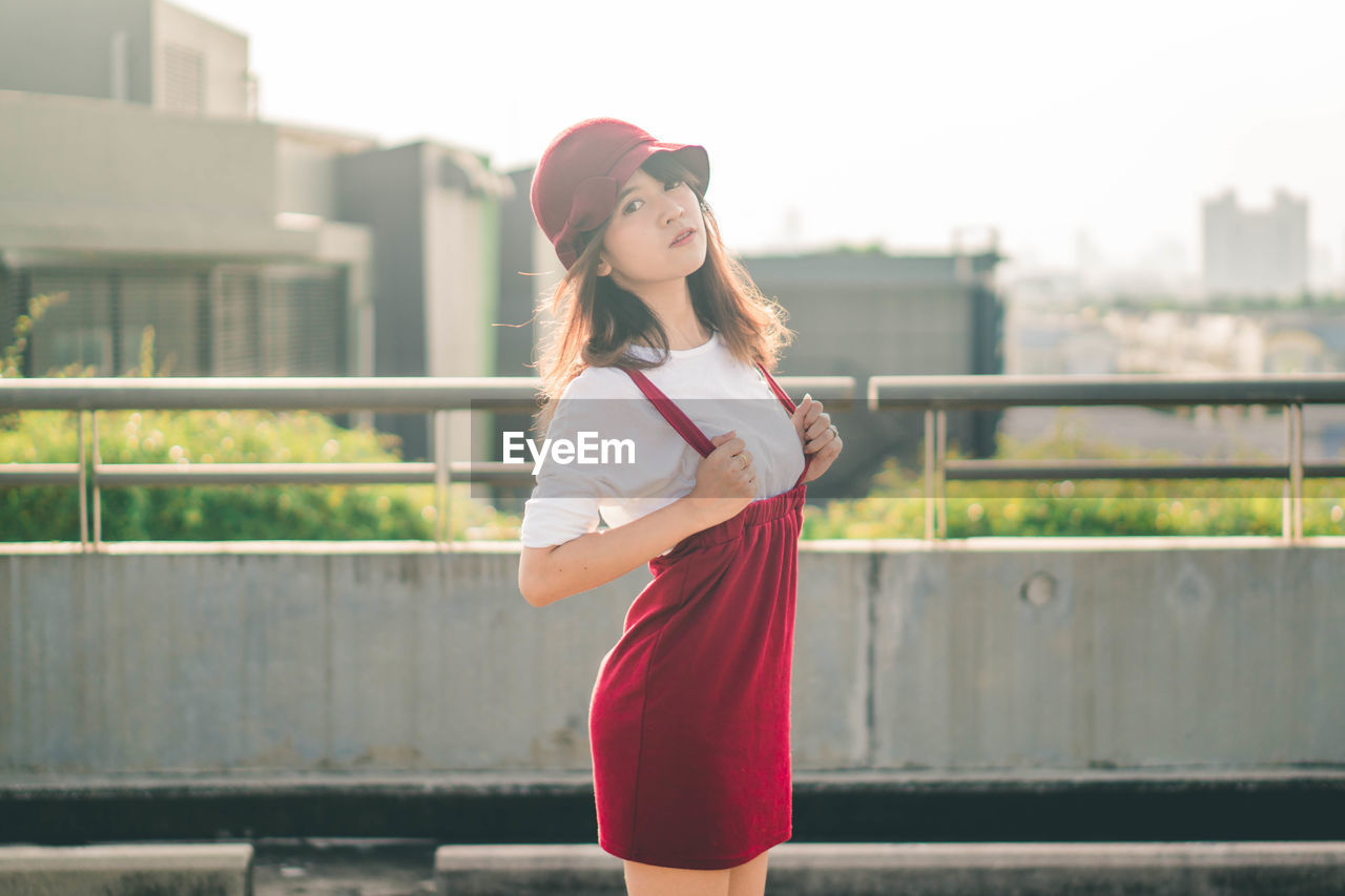 Portrait of woman standing on building terrace against railing