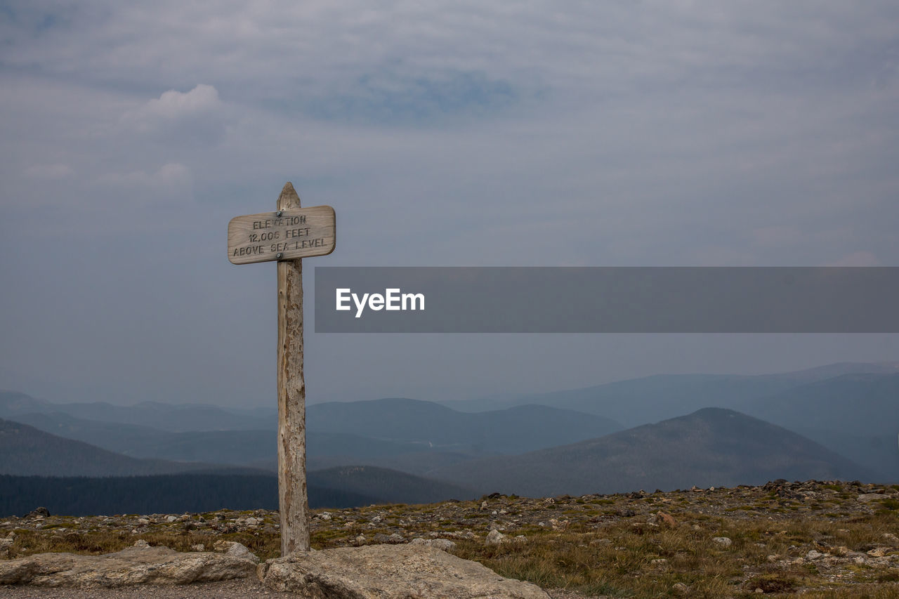 VIEW OF ROAD SIGN AGAINST MOUNTAIN RANGE