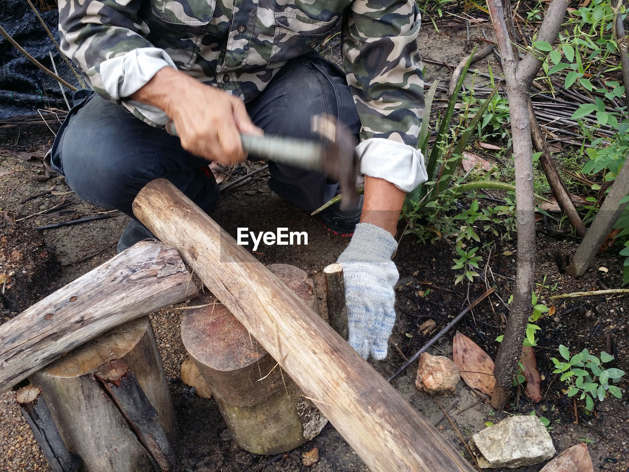 Full length of man holding log in forest