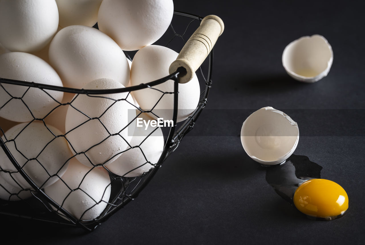 Close-up of broken egg by basket on table