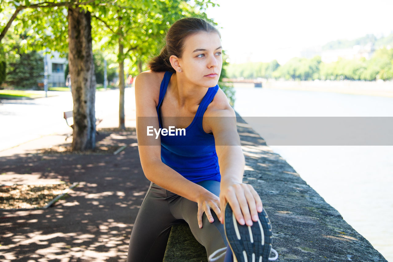 Teenage girl exercising on retaining wall