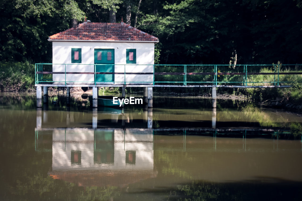 BUILT STRUCTURE BY LAKE AGAINST BUILDING