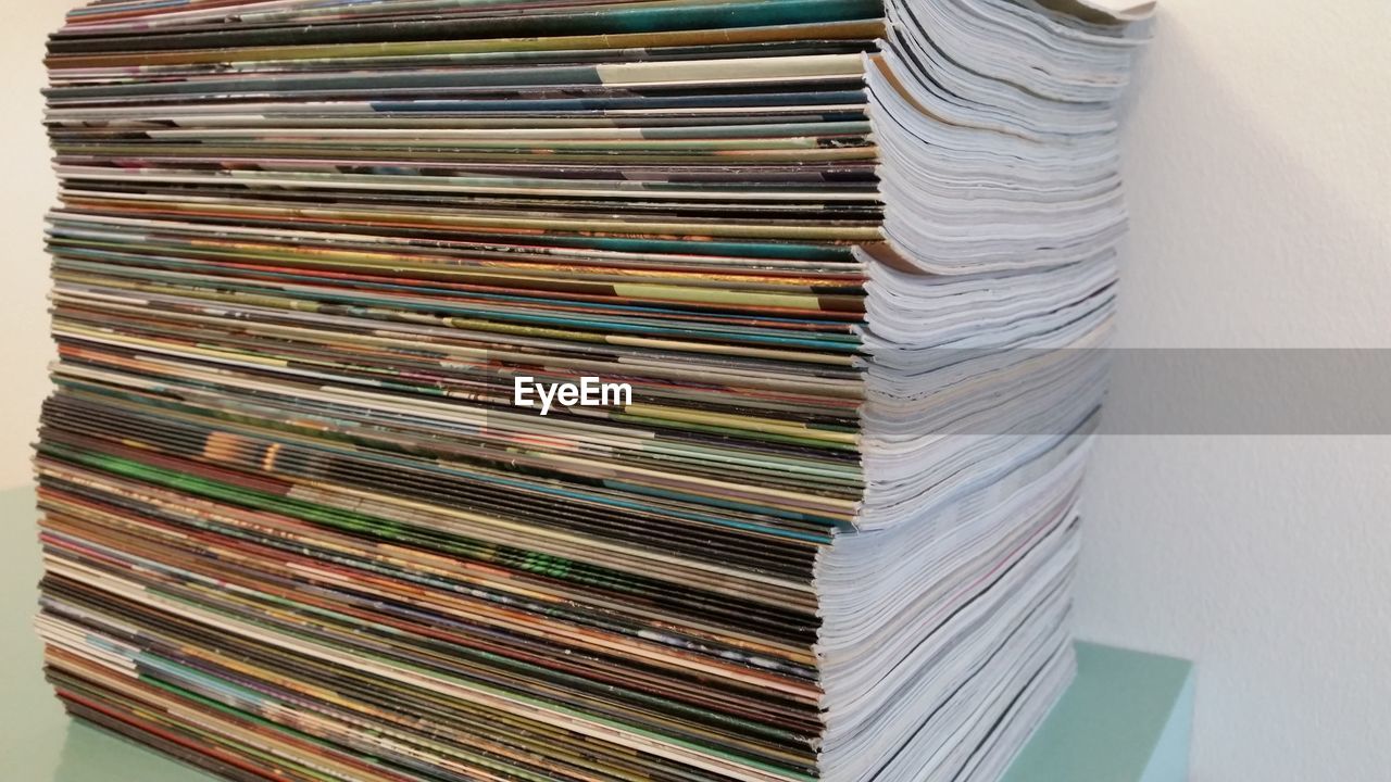 Stack of magazines on table against wall