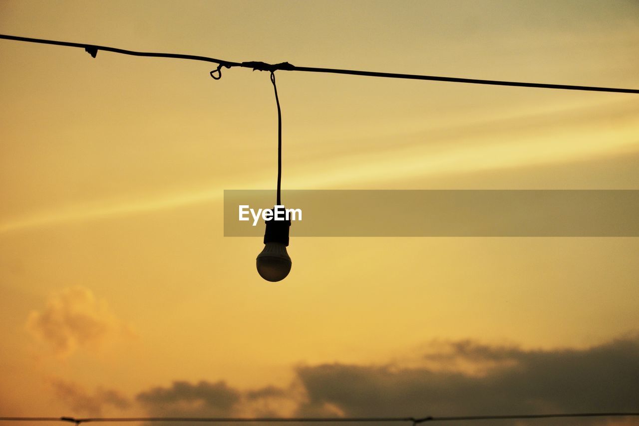 hanging, sky, sunset, light, silhouette, cable, cloud, lighting, nature, yellow, evening, no people, dusk, light fixture, rope, sunlight, low angle view, orange color, electricity, outdoors, line, street light, wire, sun, water, reflection