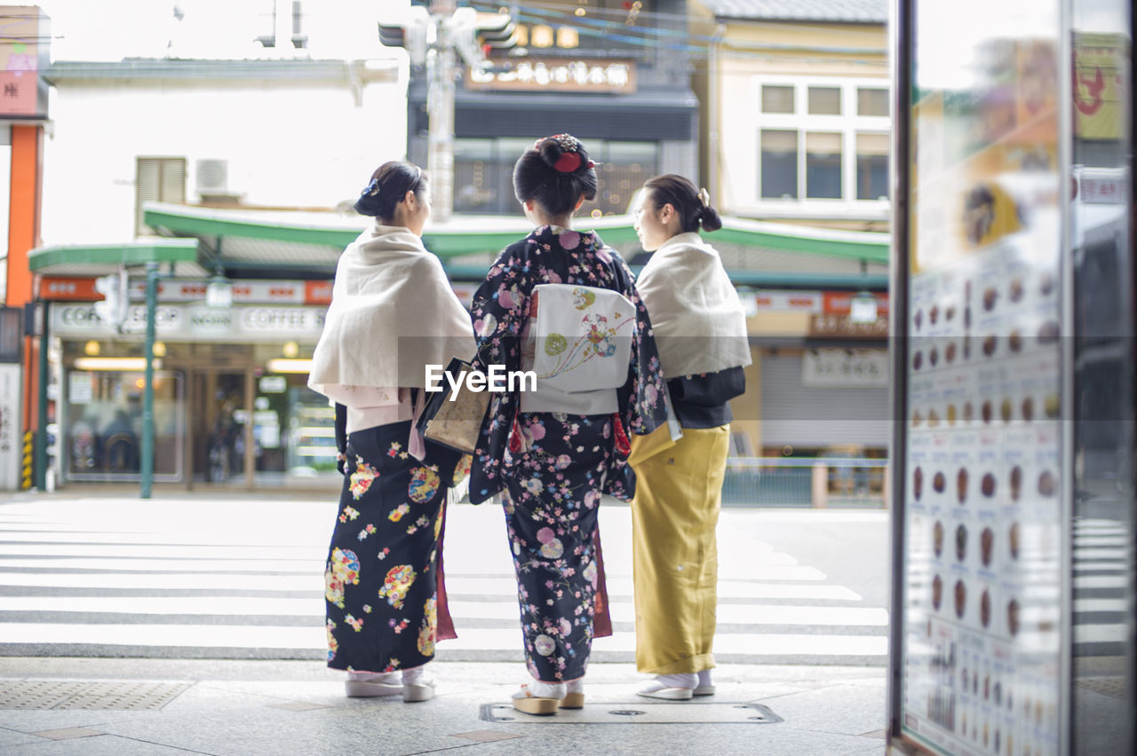 REAR VIEW OF PEOPLE WALKING ON STREET