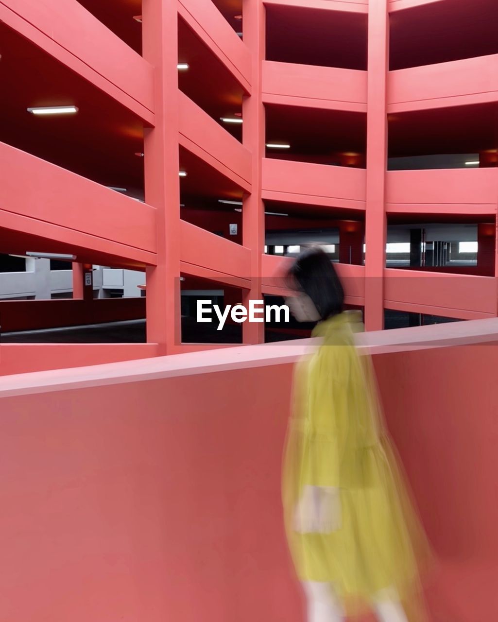 REAR VIEW OF WOMAN WITH RED UMBRELLA WALKING IN CORRIDOR