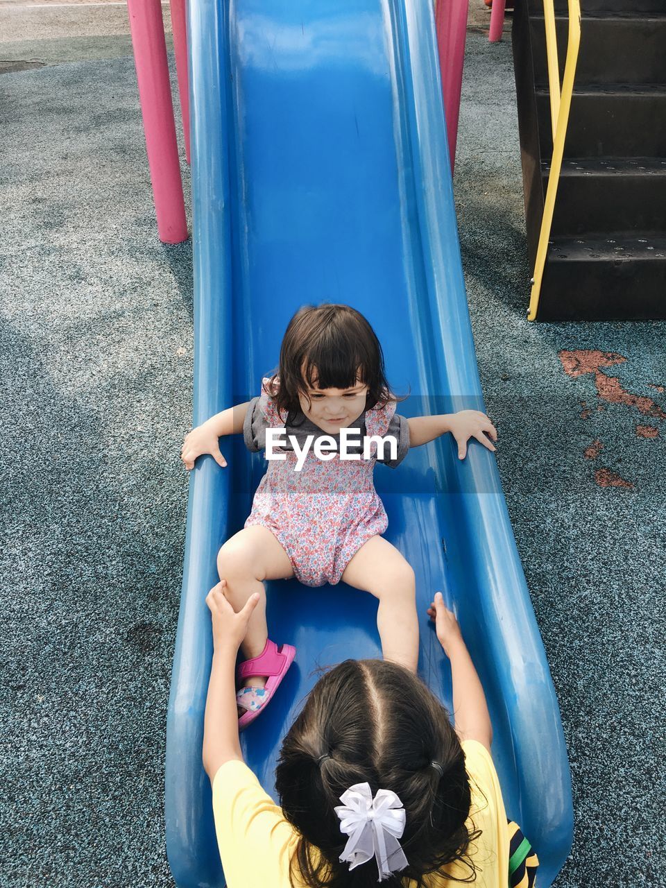 High angle view of siblings playing on slide at playground