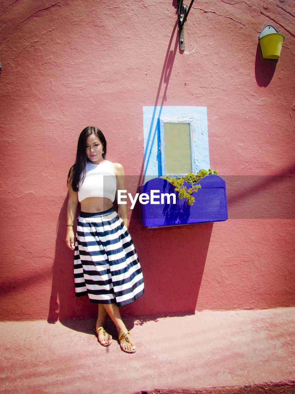 Portrait of young woman standing against wall