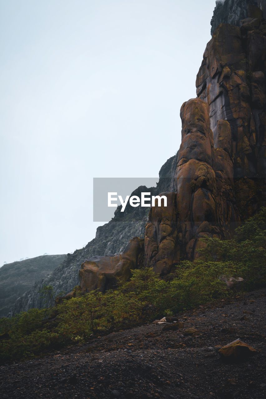 LOW ANGLE VIEW OF ROCK FORMATIONS AGAINST CLEAR SKY