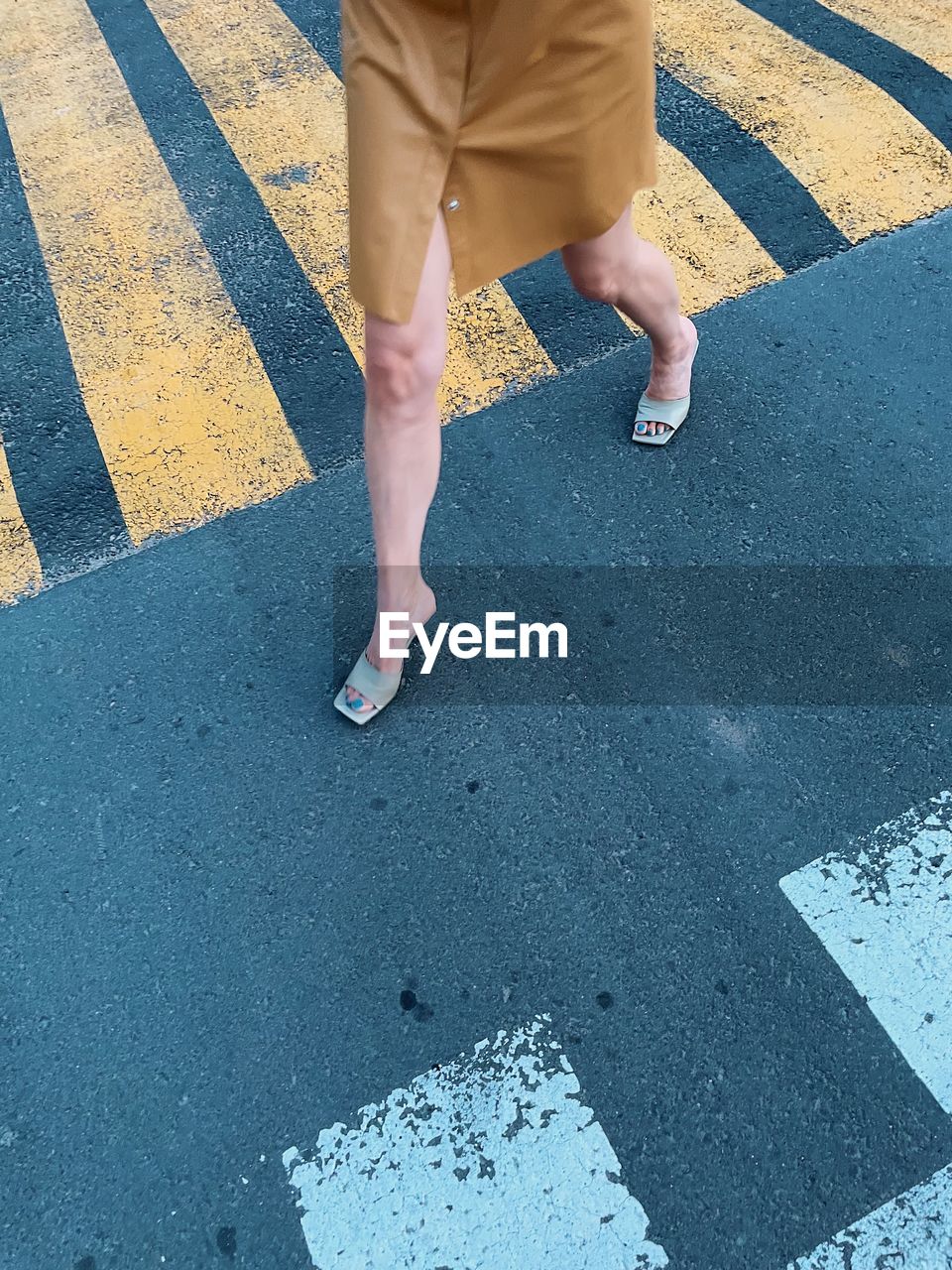 LOW SECTION OF WOMAN WALKING ON ROAD