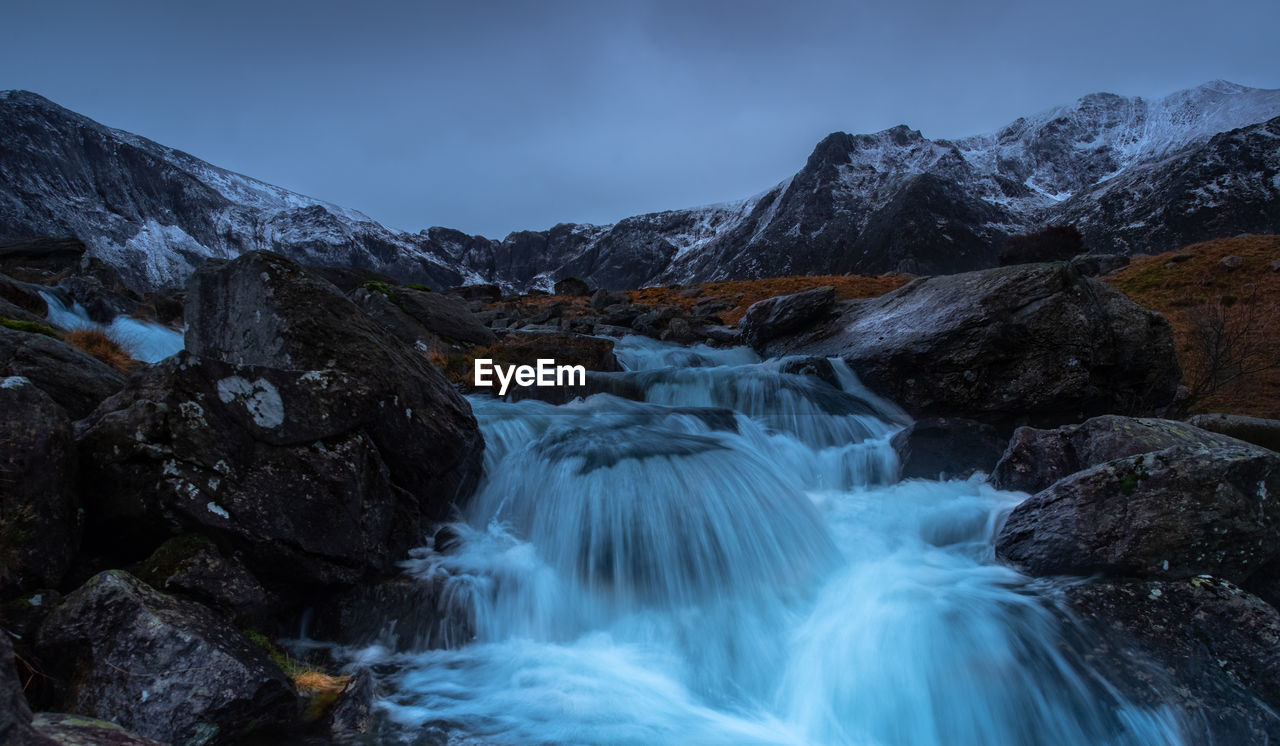 SCENIC VIEW OF WATERFALL AGAINST ROCKS