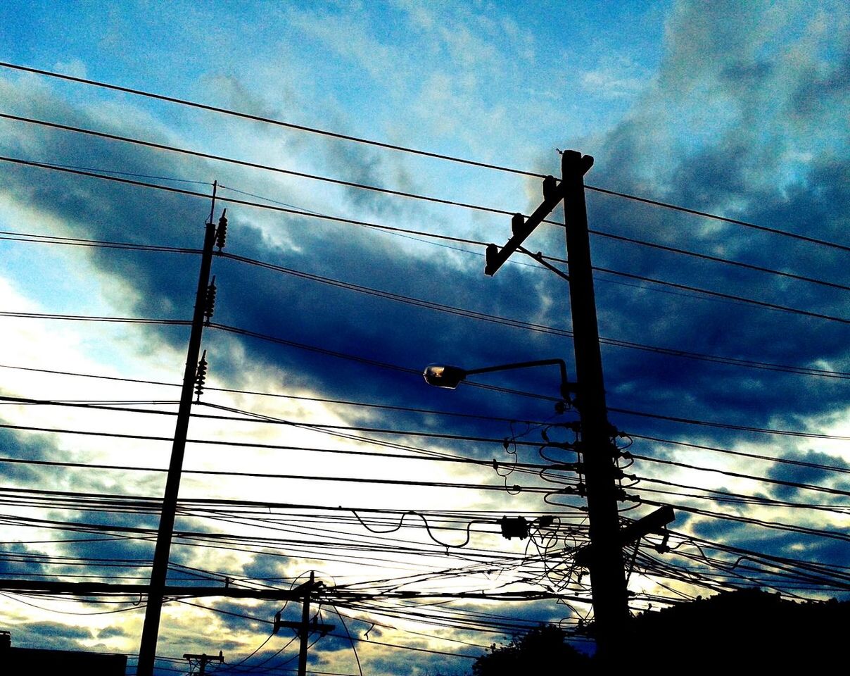 Low angle view of silhouette power lines against blue sky at dusk