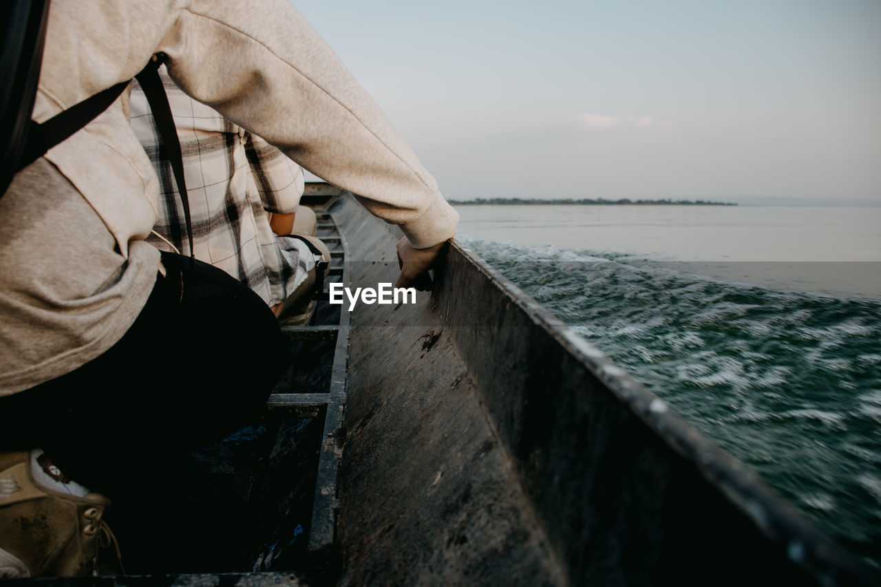 MAN STANDING ON BOAT AGAINST SEA