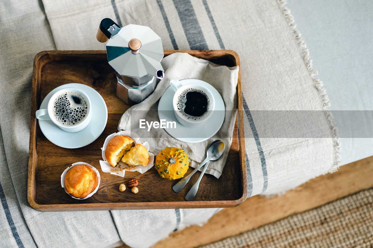 Morning coffee with pumpkin muffins on a wooden tray.