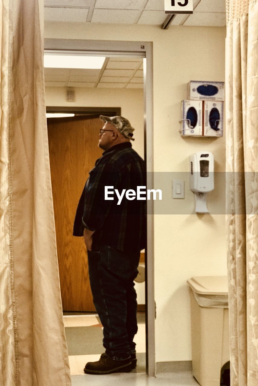 SIDE VIEW OF MAN PHOTOGRAPHING IN BATHROOM