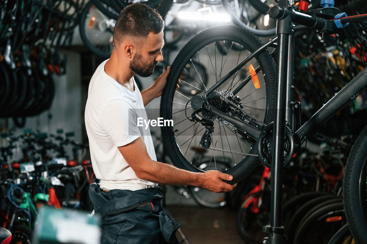 side view of man holding bicycle