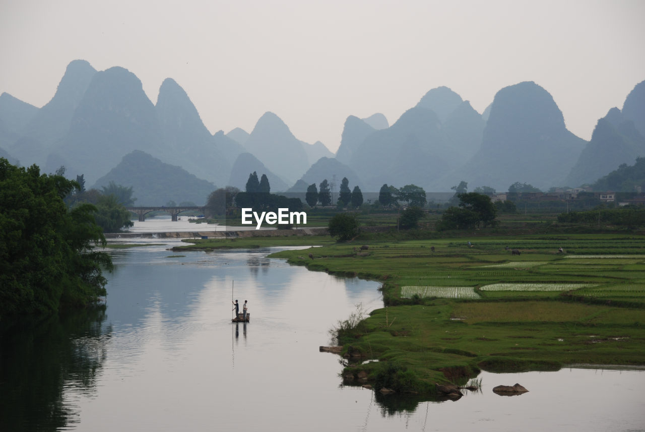 High angle view of people rafting in lake against mountains and sky