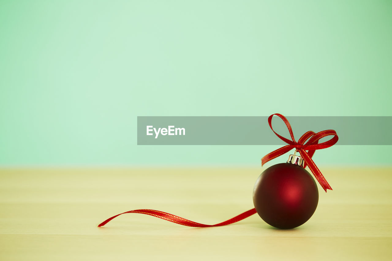 Close-up of red christmas decoration on table against wall