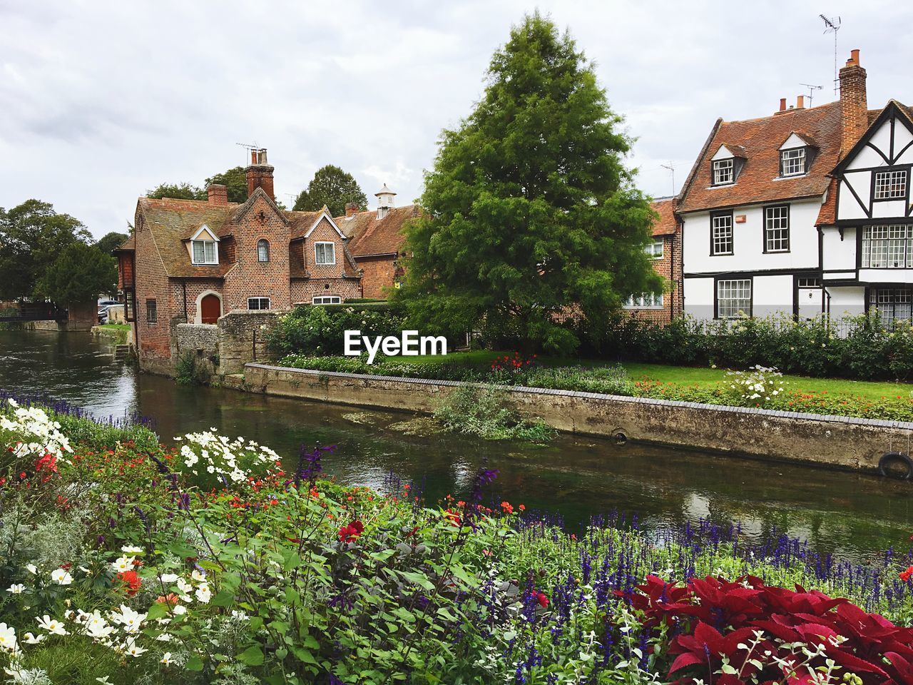 Canal amidst houses and buildings against sky