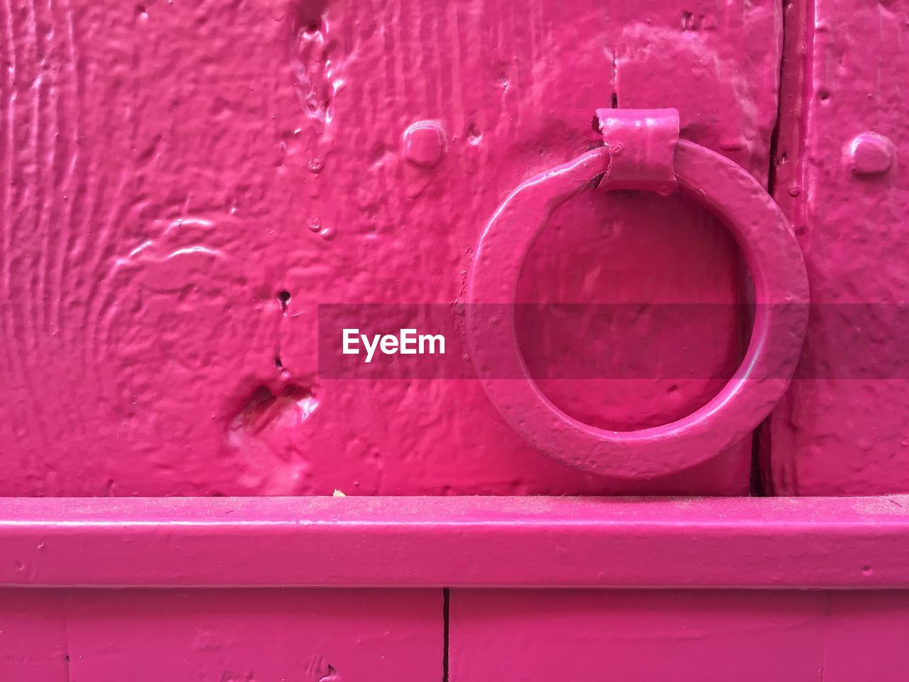 Close-up of pink metallic ring knocker on door