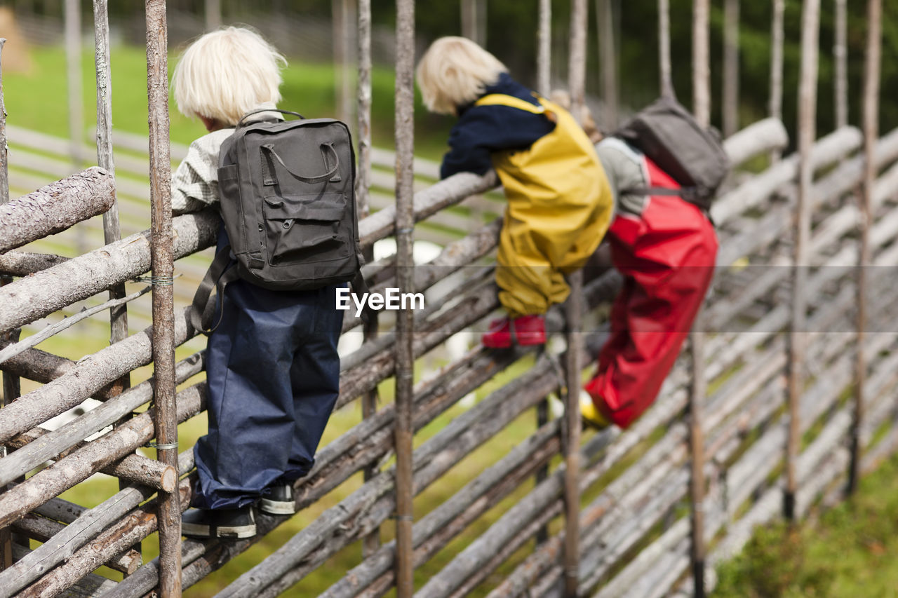 Children climbing wooden fence