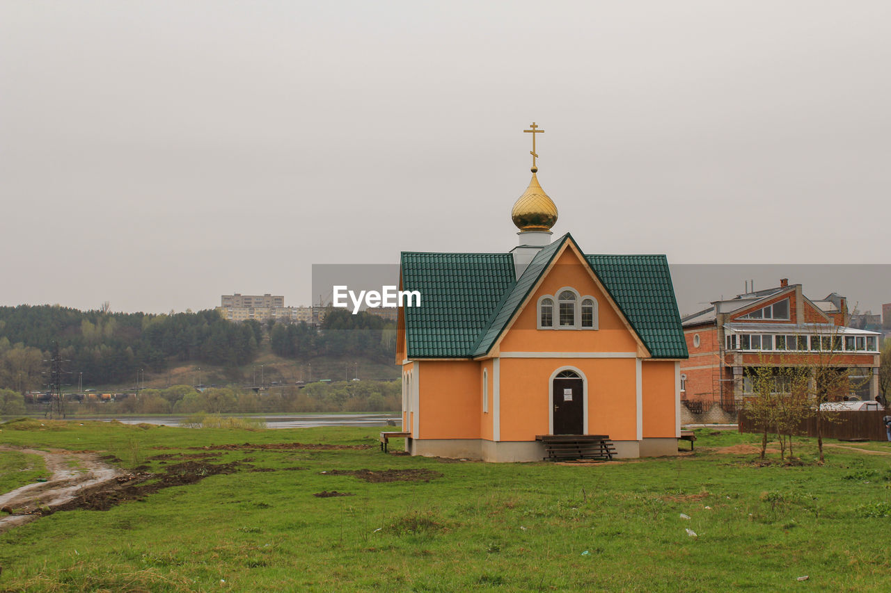 CHURCH ON FIELD AGAINST SKY