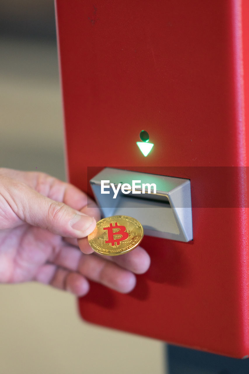 Human hand inserting a bitcoin into a vending machine. bitcoins are cryptocurrency