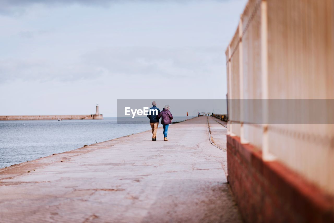 REAR VIEW OF COUPLE WALKING ON WATER