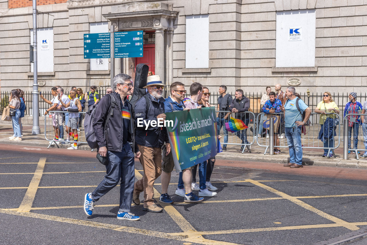 group of people, crowd, large group of people, track and field event, men, architecture, adult, full length, day, person, city, women, building exterior, occupation, long distance running, sports, sign, young adult, running, built structure, clothing