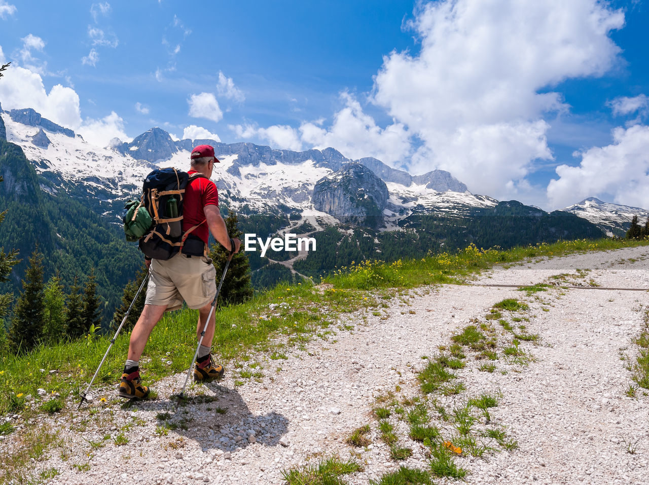 Rear view of man walking on mountain against sky