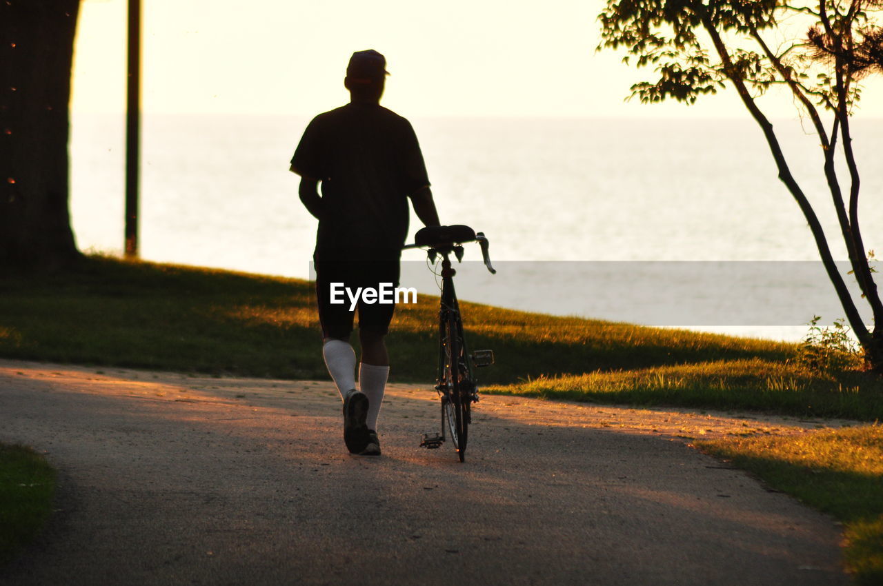 Rear view of silhouette man walking on road against sky