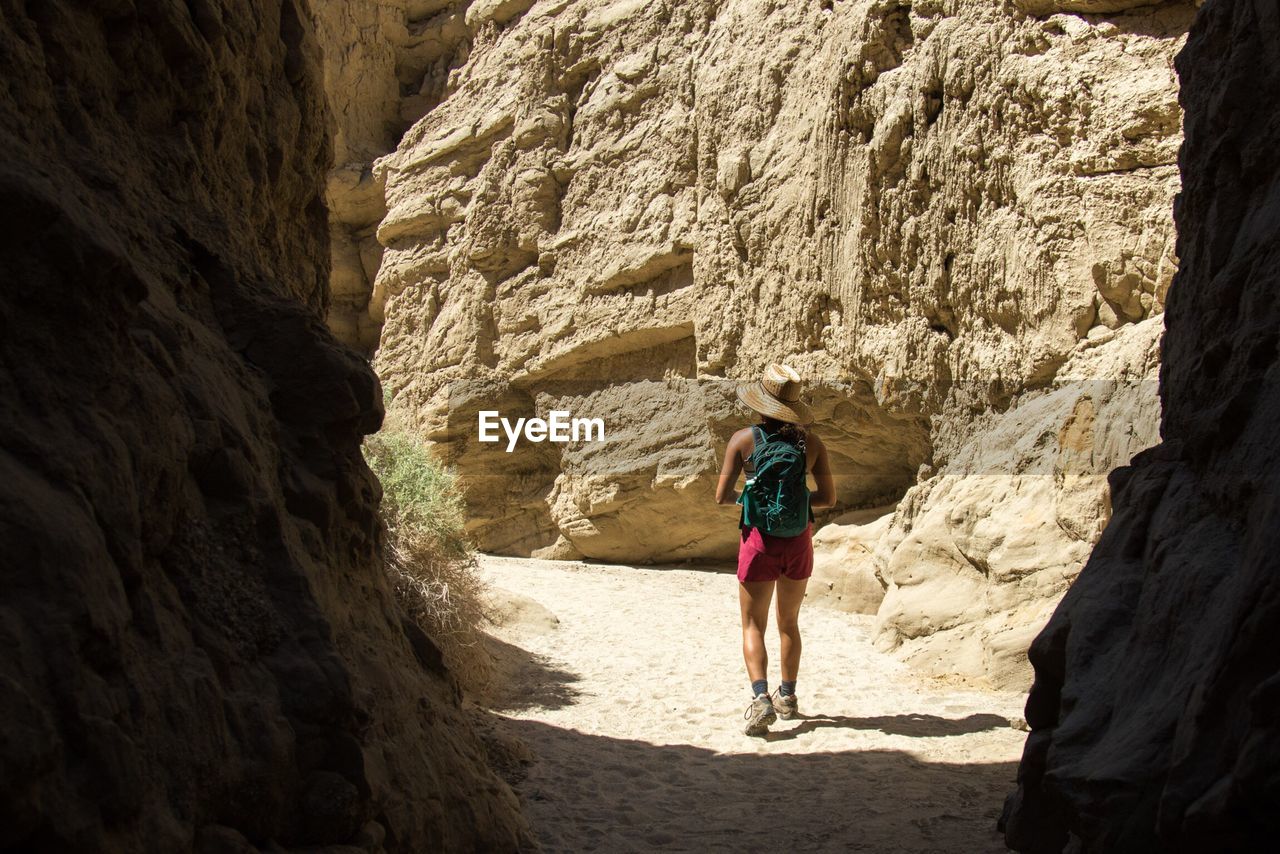 Rear view of woman walking amidst rock formation