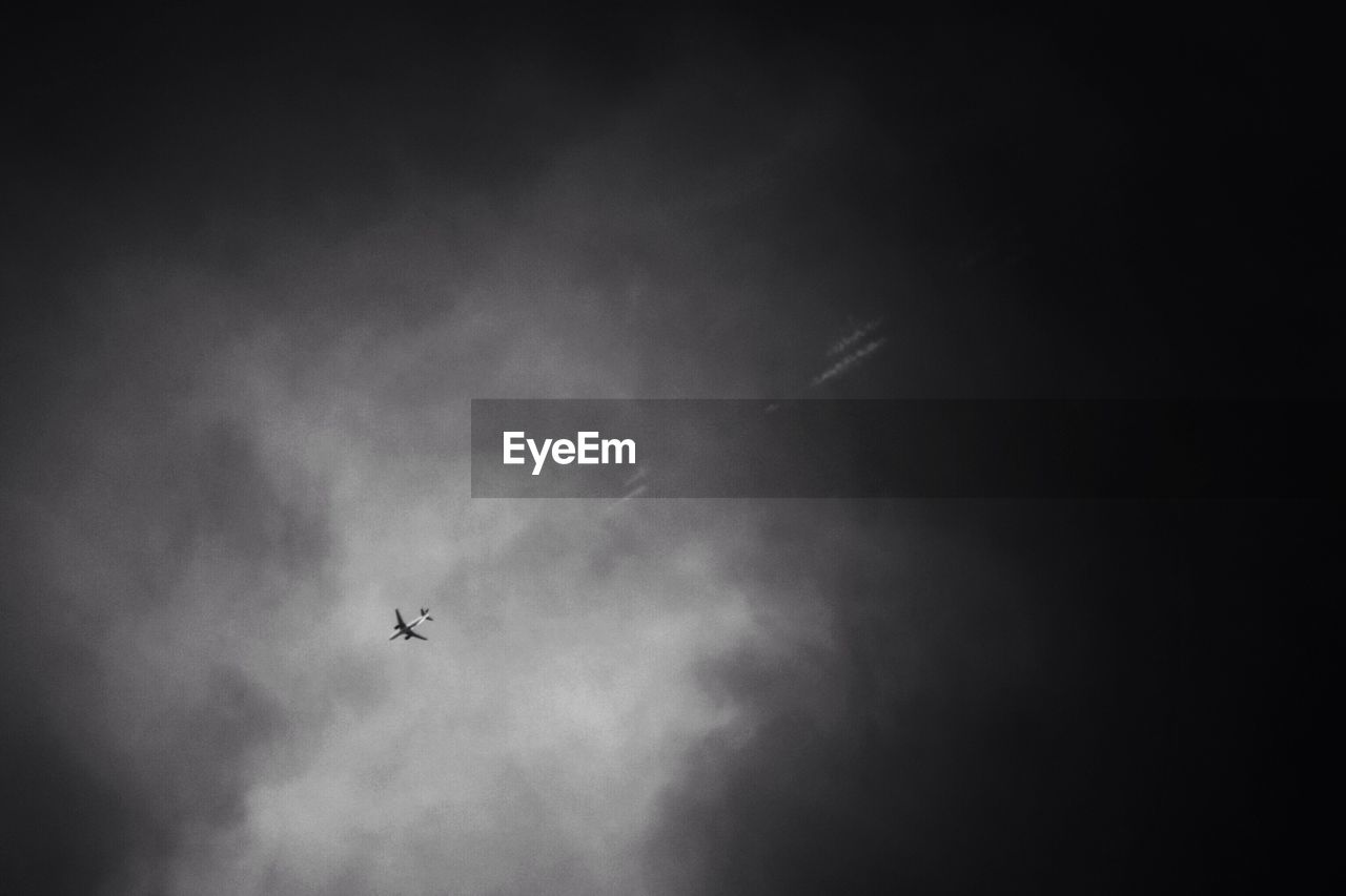 Low angle view of airplane flying against cloudy sky