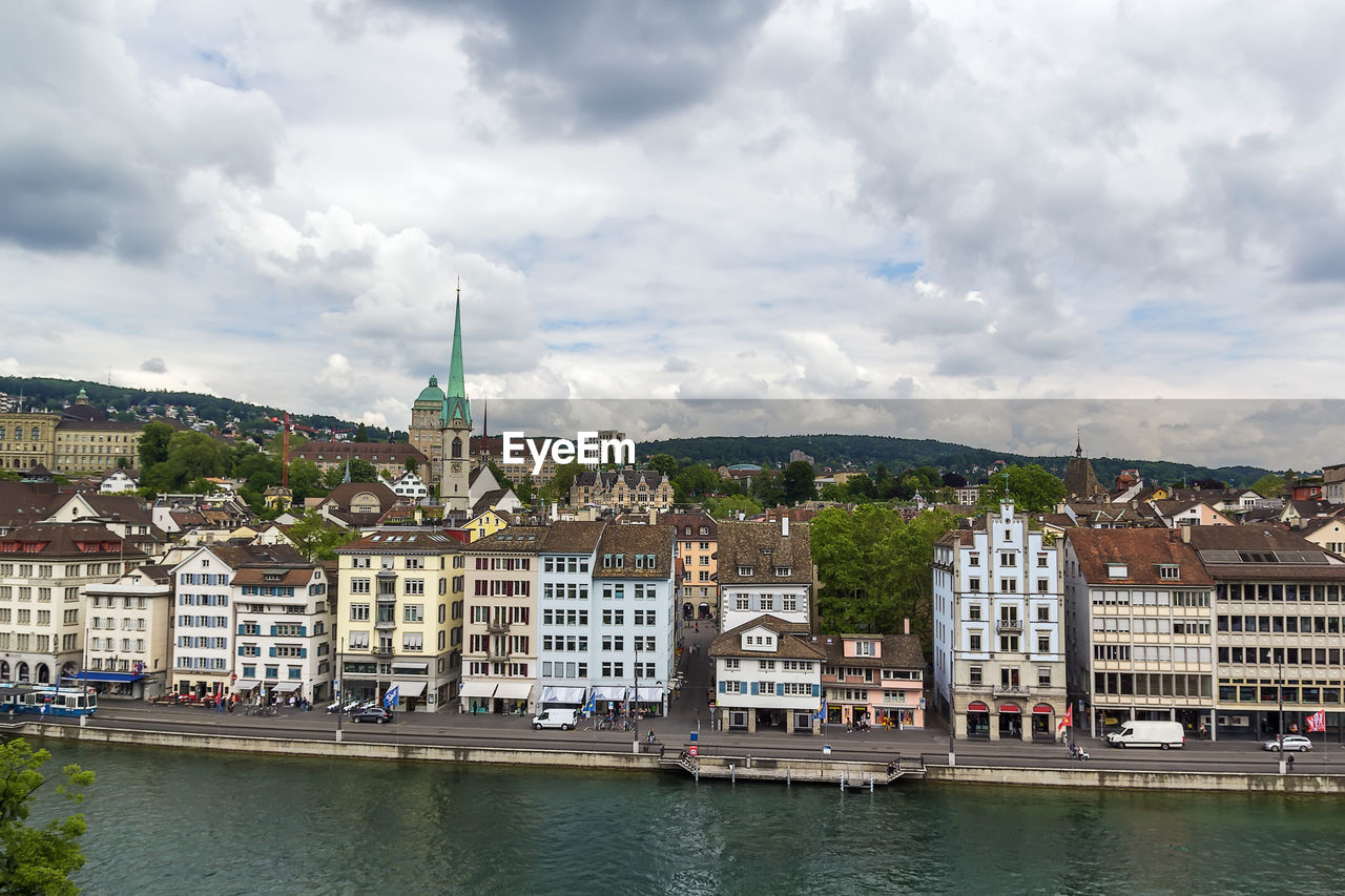 Buildings by river against sky in city