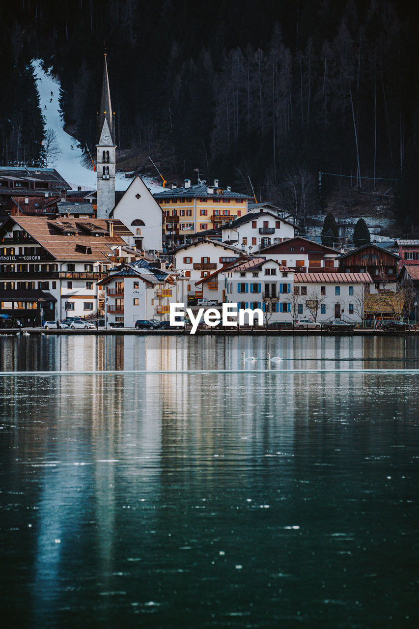 Scenic view of lake by buildings in city during winter