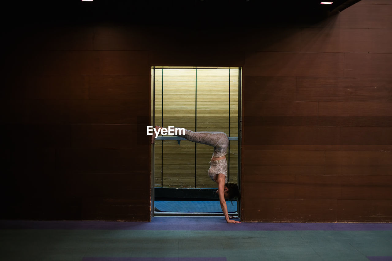 Side view of woman doing yoga at doorway