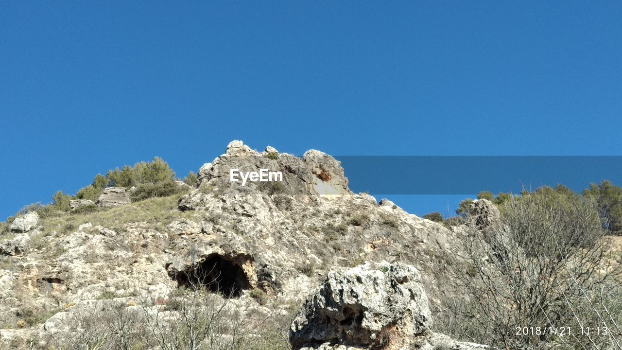 LOW ANGLE VIEW OF MOUNTAIN AGAINST BLUE SKY