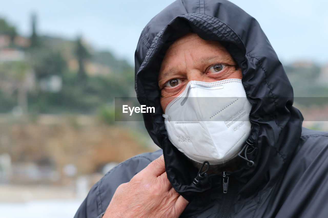 Portrait of senior man wearing mask standing outdoors