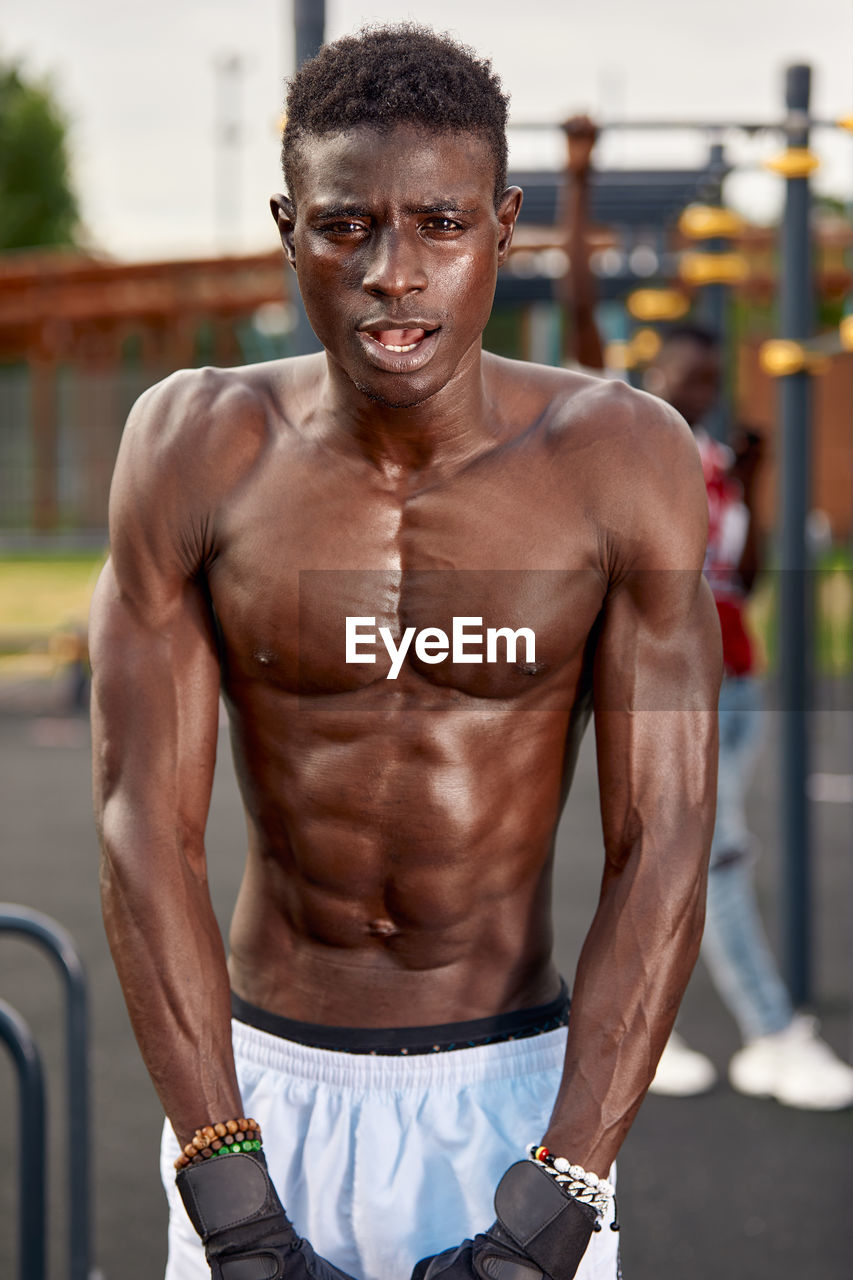 portrait of shirtless man exercising at gym