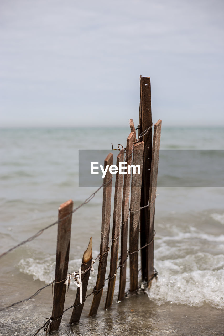 Wooden posts on beach against sky