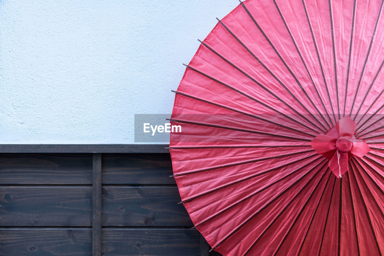 LOW ANGLE VIEW OF UMBRELLA ON WOOD AGAINST WALL