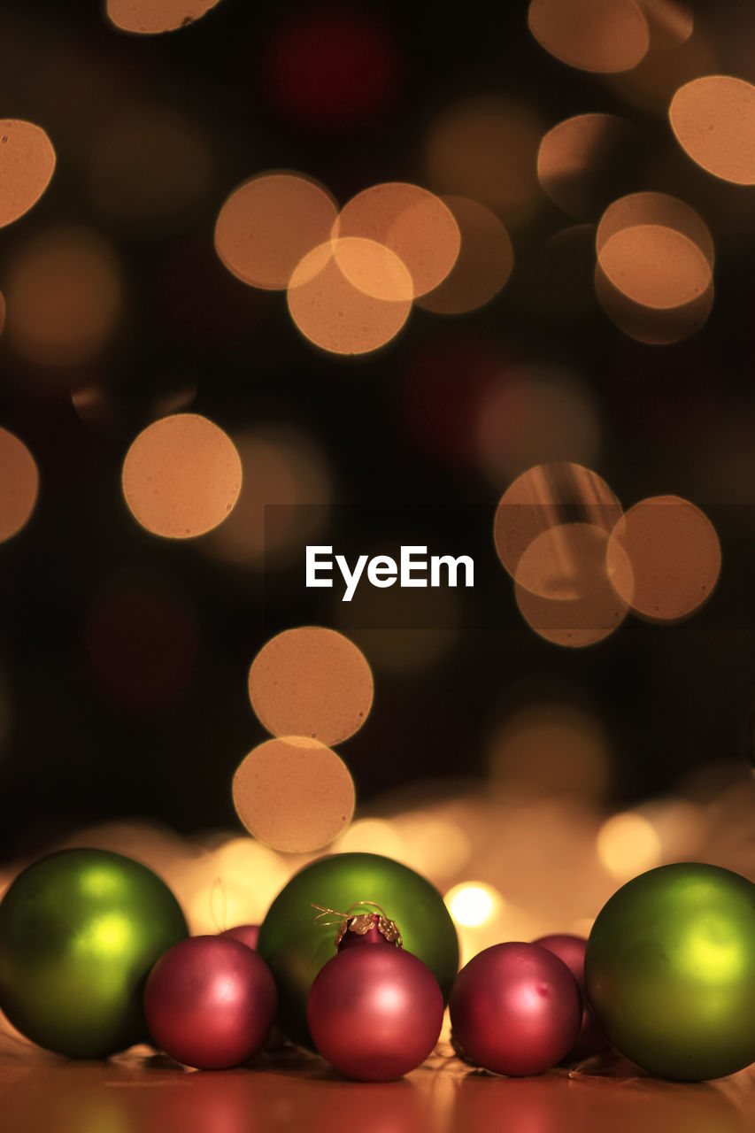 Close-up of illuminated christmas lights and green and purple christmas balls