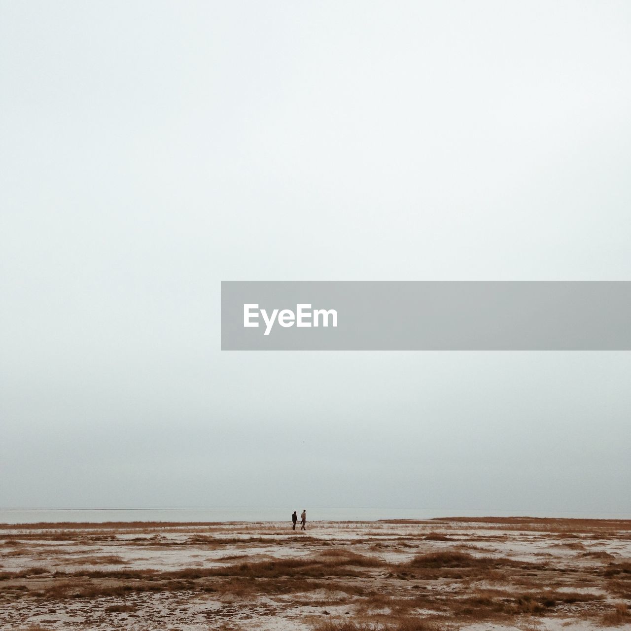 MAN STANDING IN SEA AGAINST CLEAR SKY