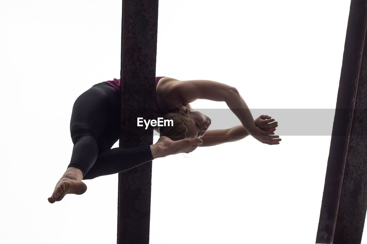 Low angle view of gymnast performing on balance beam against clear sky