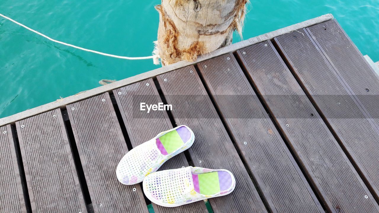 High angle view of shoes on jetty over swimming pool