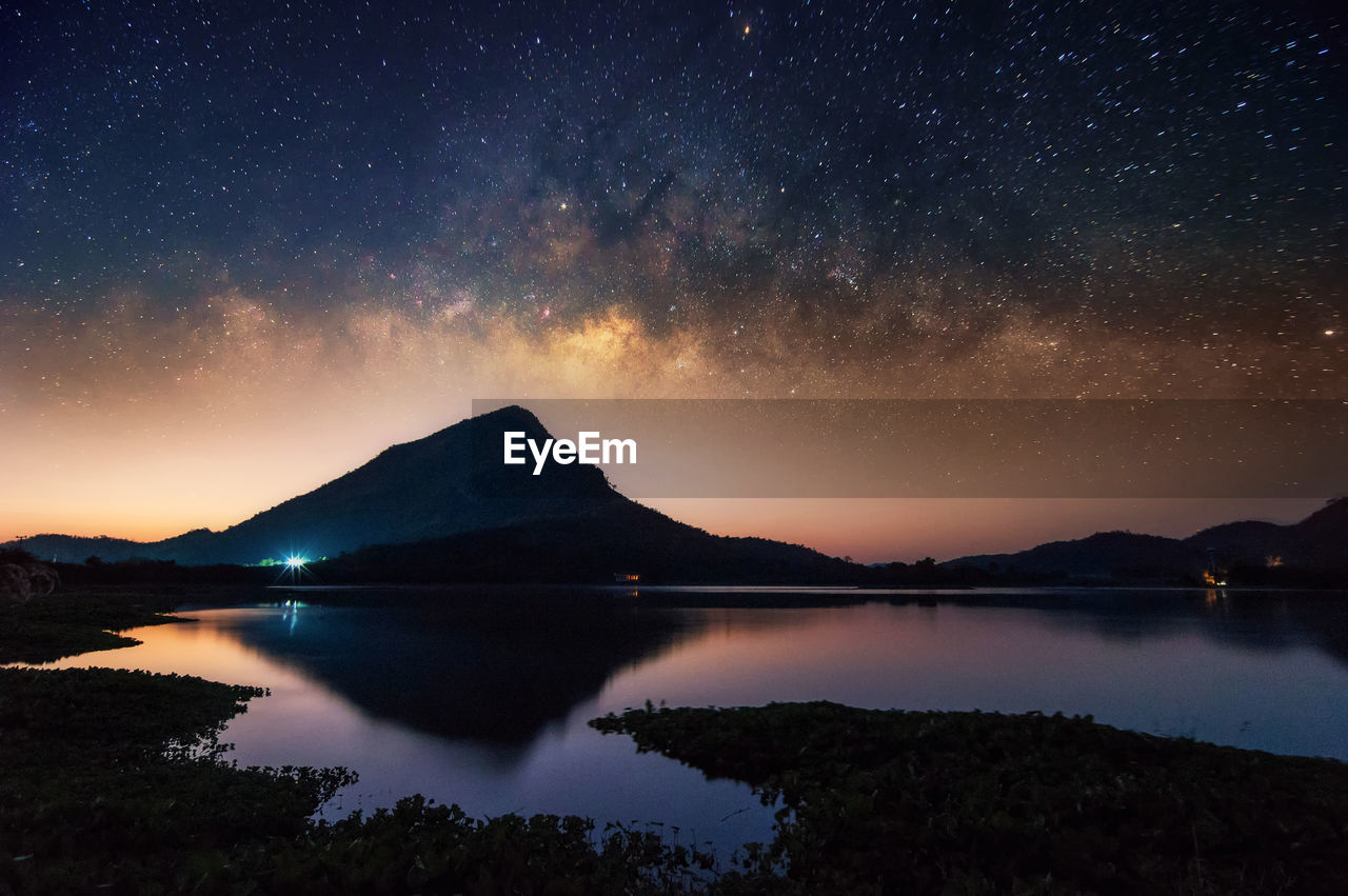 Scenic view of lake and mountains against sky at night