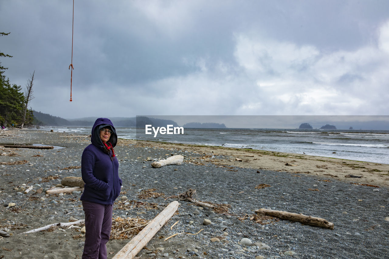 Portrait of woman standing at beach against sky