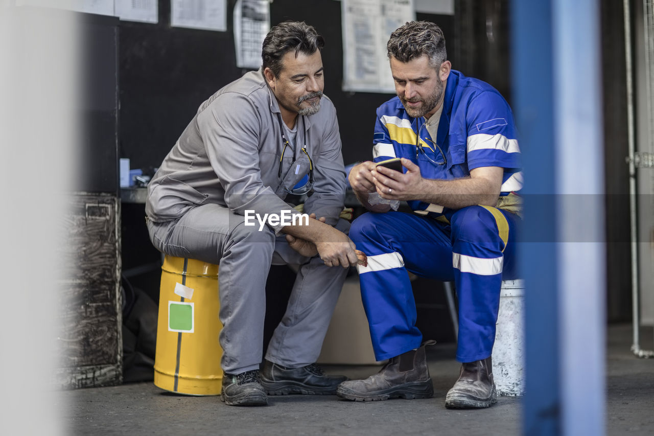 Two workers having a break looking at cell phone