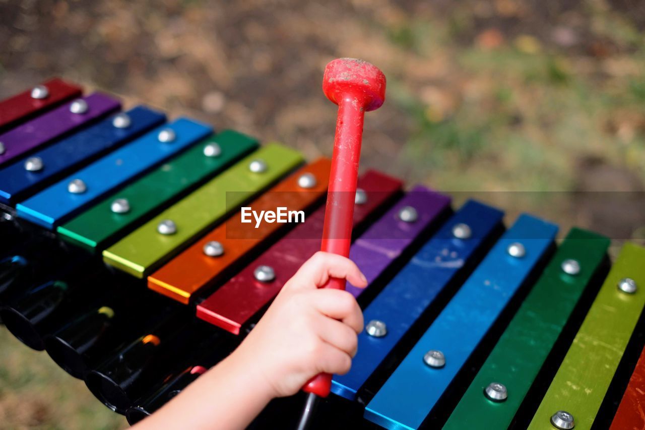 Cropped hand of child playing xylophone outdoors