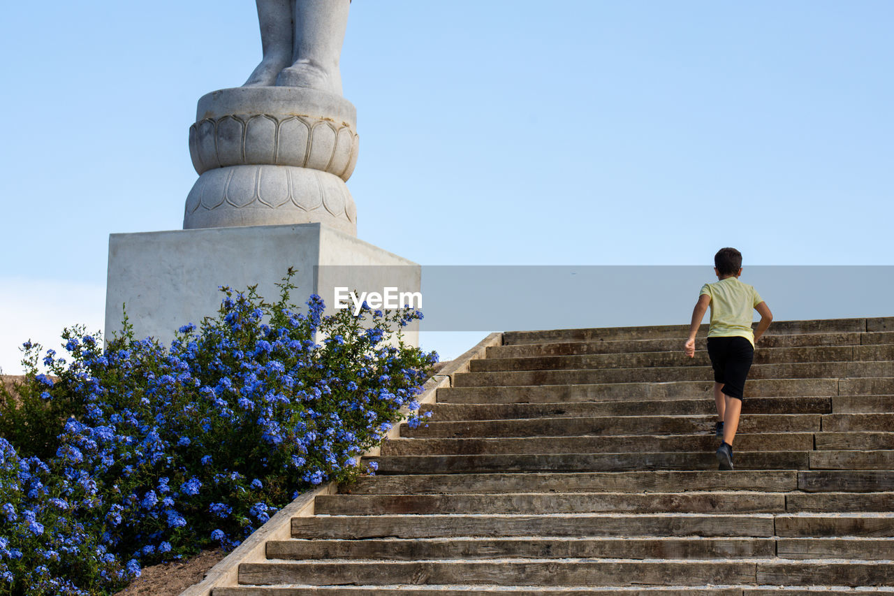 LOW ANGLE VIEW OF MAN WALKING ON STAIRCASE